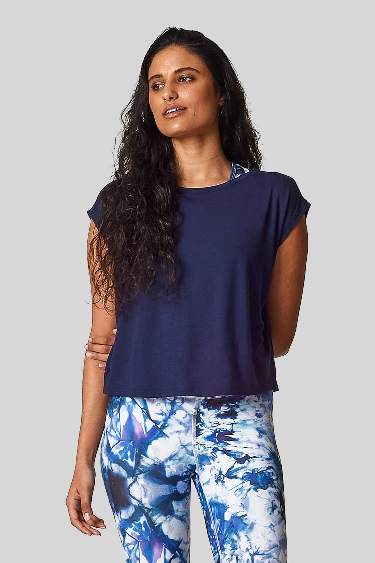 A brunette is wearing a navy marine box tee with an exclusive printed legging.
