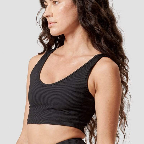 The side profile of a woman modeling a black reversible sports bra.