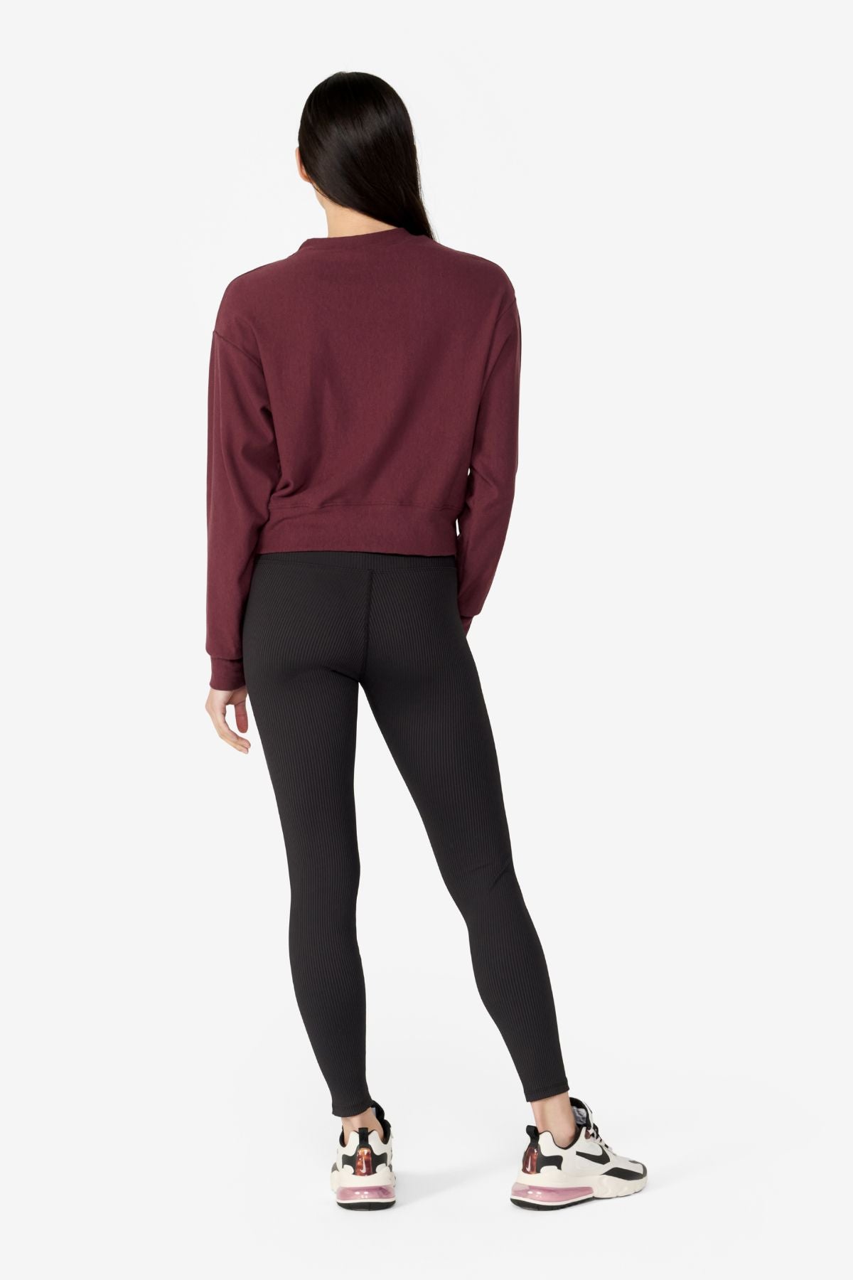 girl back side wearing a dark red long sleeves sweater with black leggings