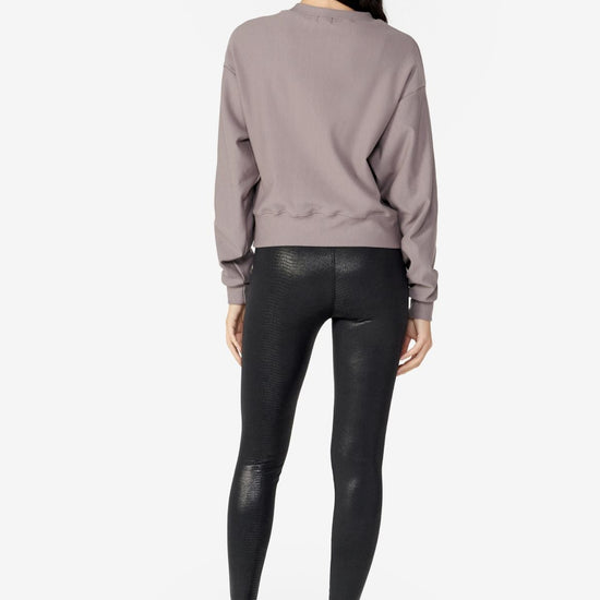girl back side wearing a light grey long sleeves sweater with black leggings