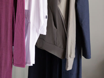 A photo of 2 shirts, 1 sweatshirt and a jacket on a rack to illustrate an intentional closet.
