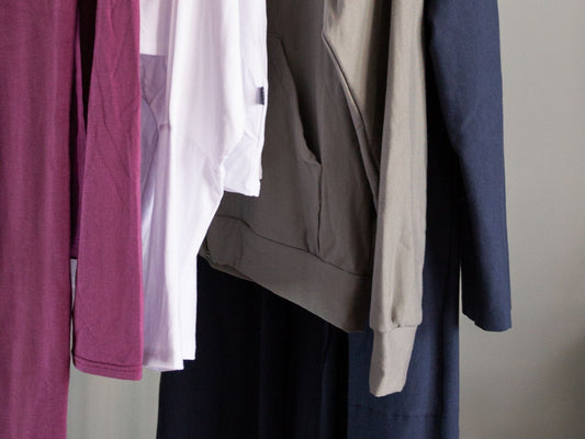 A photo of 2 shirts, 1 sweatshirt and a jacket on a rack to illustrate an intentional closet.