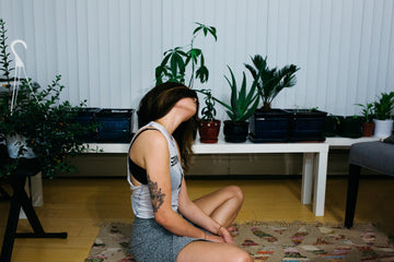 Woman doing yoga in her living room with plants.