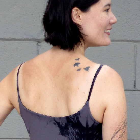 Woman with tattoos wearing a grey swim top