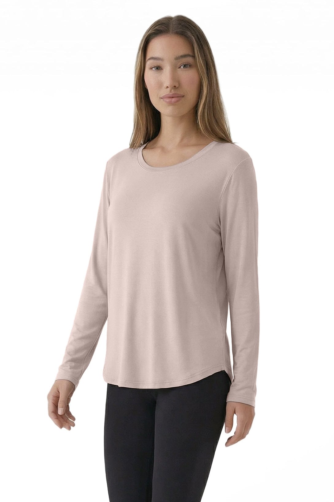 Woman wearing a light pink long-sleeve top and black pants on a white background