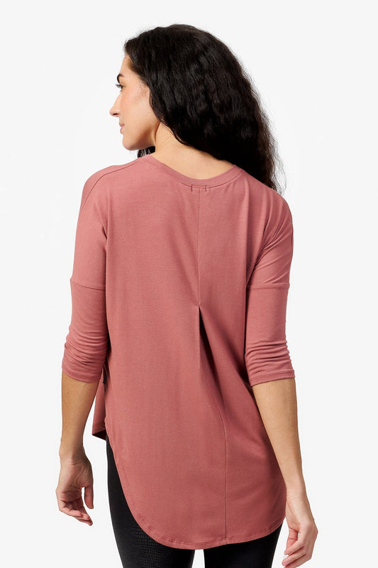 Back of a woman  wearing a light rust 3/4 length sleeve shirt