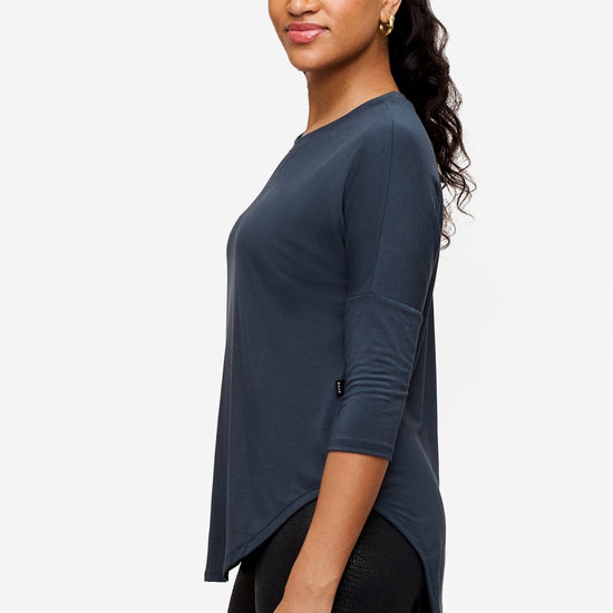 Side of a woman wearing a dark blue 3/4 sleeve shirt