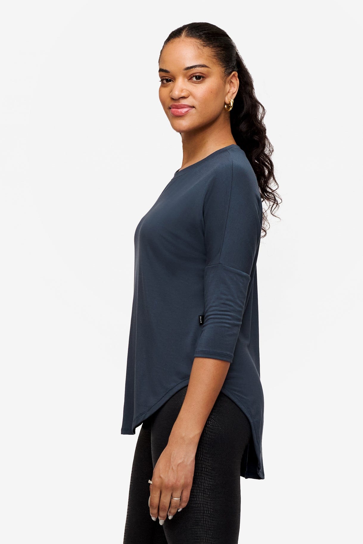 Side of a woman wearing a dark blue 3/4 sleeve shirt