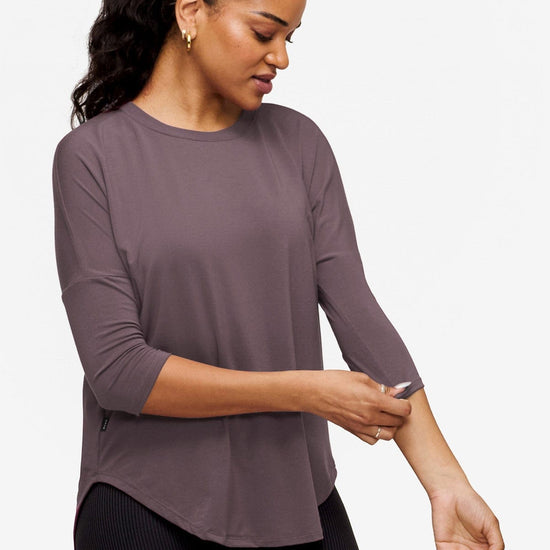 side of a woman wearing a 3/4 sleeve shirt in purple