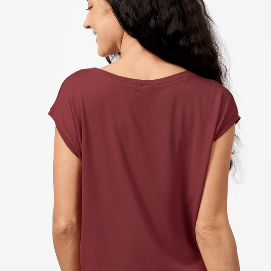 A brunette woman models a burgundy tee shirt. This photo shows the back view of the top which is made from modal and drapes beautifully.