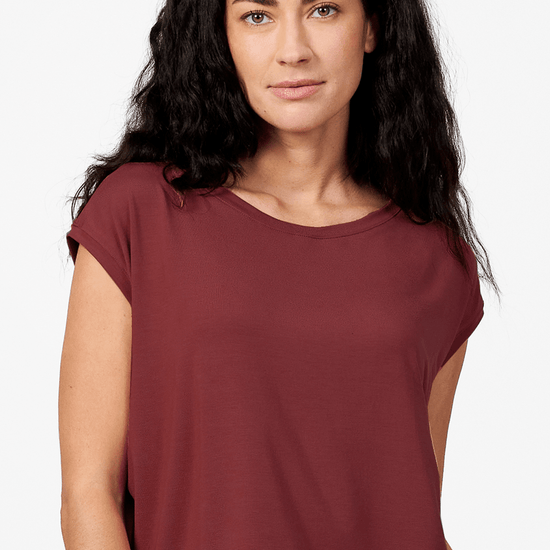 A brunette woman wears a hip length, red t-shirt made in Canada.