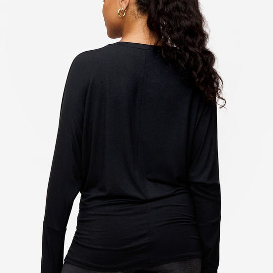 back of a  woman wearing a black loose dolman sleeve long sleeve shirt