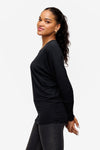 side of a woman wearing a black loose dolman sleeve long sleeve shirt