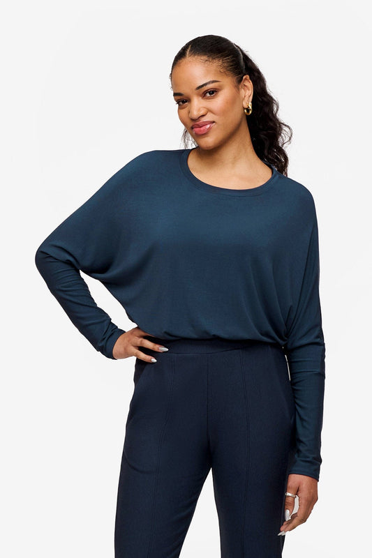 Woman wearing a long sleeve tee with dolman sleeves tucked in and her hand on her waist