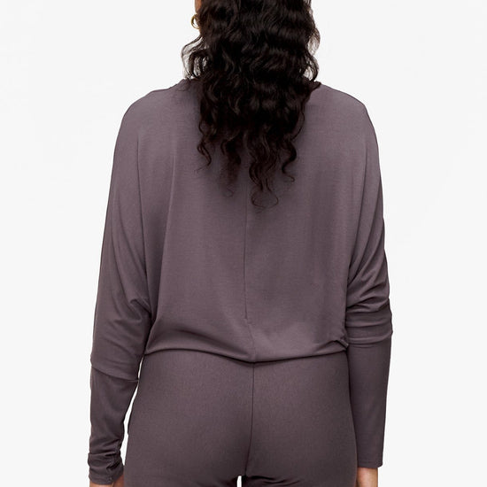 back of a woman wearing a deep purple loose sleeve long sleeve shirt