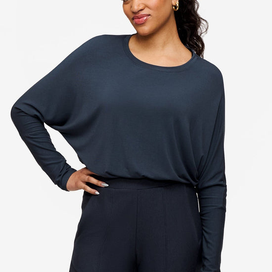 smiling woman wearing a dark blue loose sleeve long sleeve shirt