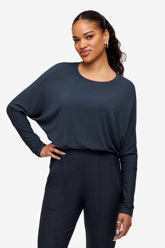 smiling woman wearing a dark blue loose sleeve long sleeve shirt