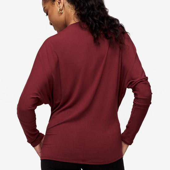 back of a woman wearing a dark red loose sleeve long sleeve shirt