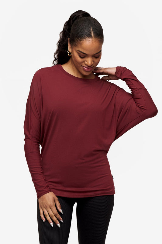 woman looking down wearing a dark red loose sleeve long sleeve shirt