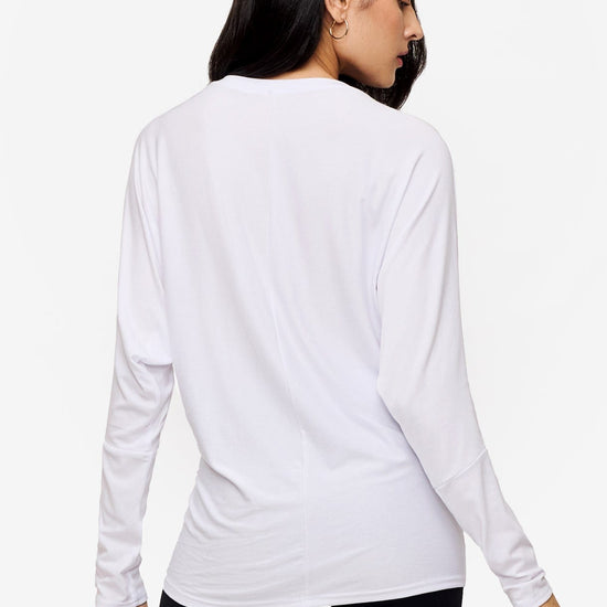 back of a woman wearing a white loose sleeve long sleeve shirt