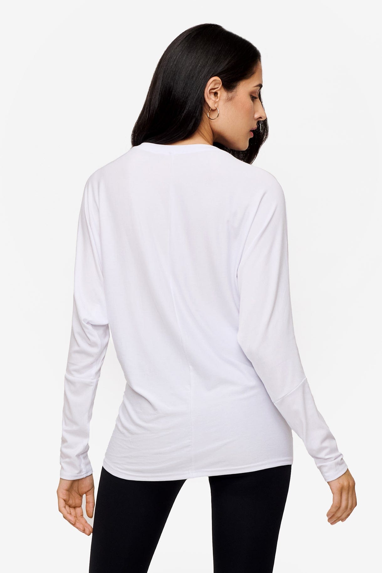 back of a woman wearing a white loose sleeve long sleeve shirt