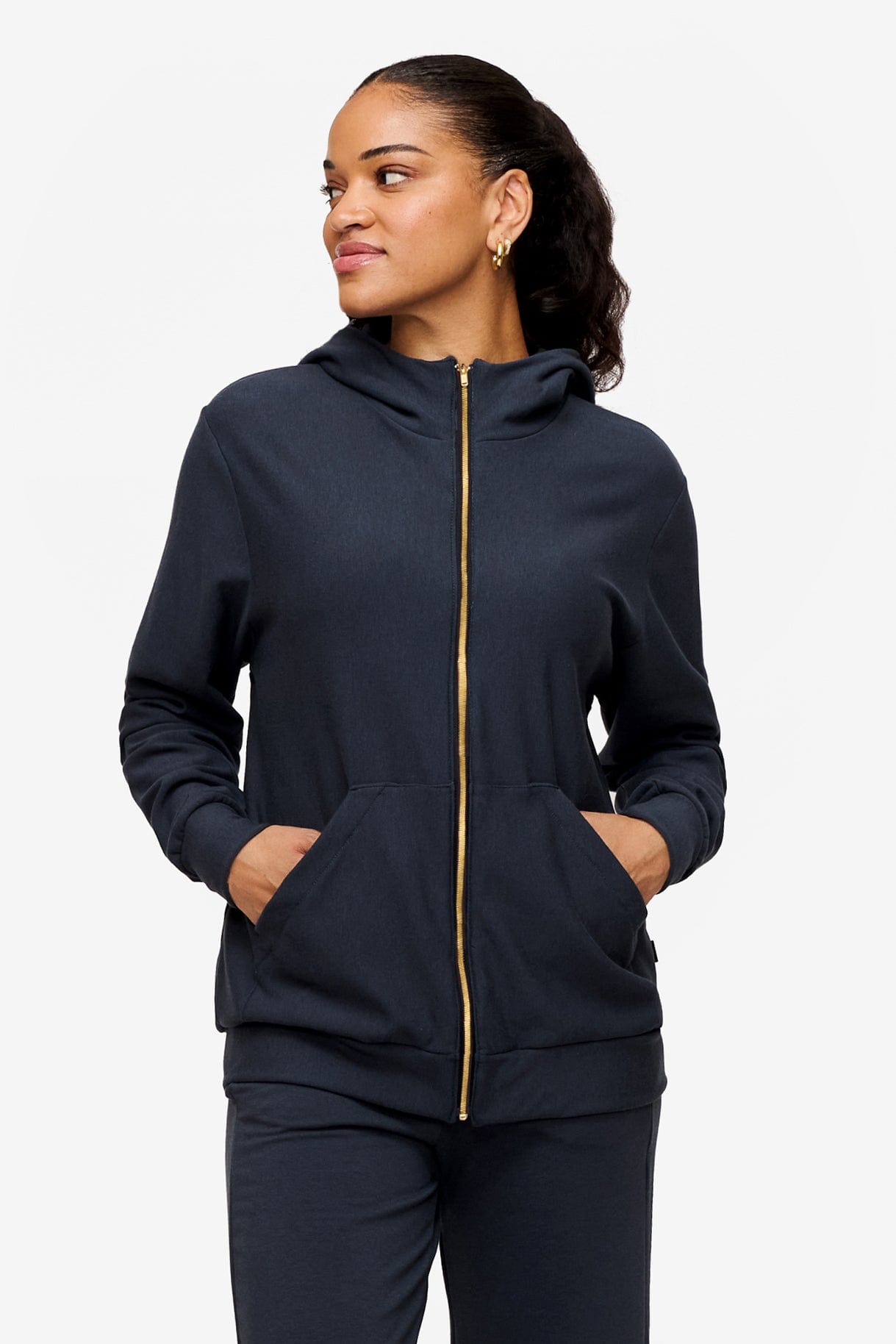 woman wearing full zip hoodie in dark blue with her hands in pockets