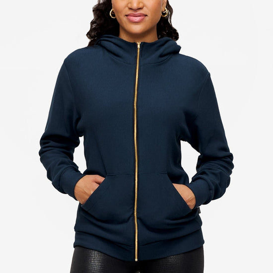 woman wearing full zip hoodie in blue  with hands in the pockets 