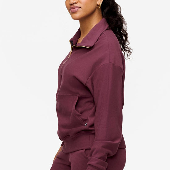 side of a woman wearing half zip sweatshirt in deep pink