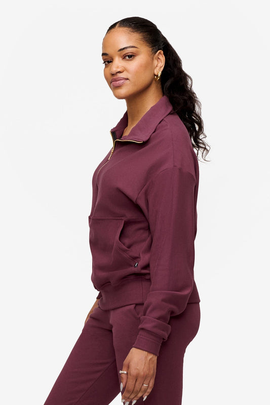 side of a woman wearing half zip sweatshirt in deep pink