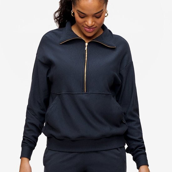 woman looking sown wearing half zip sweatshirt in dark blue 