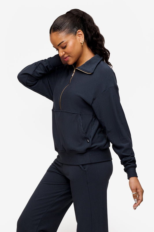 side of a woman wearing half zip sweatshirt in dark blue 