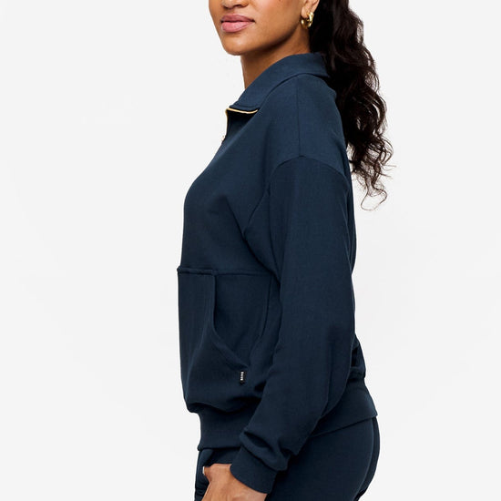 side of woman wearing half zip sweatshirt in deep blue 