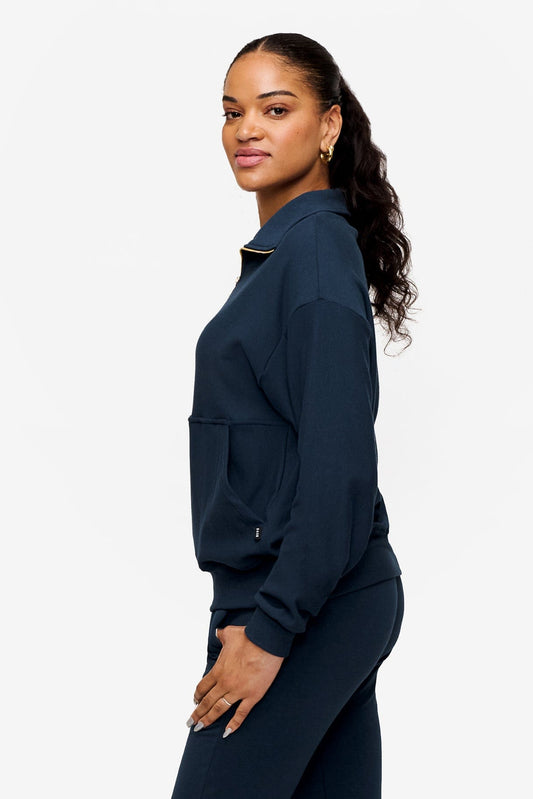 side of woman wearing half zip sweatshirt in deep blue 