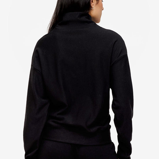 back of a woman wearing a 1/4 zip sweatshirt in black