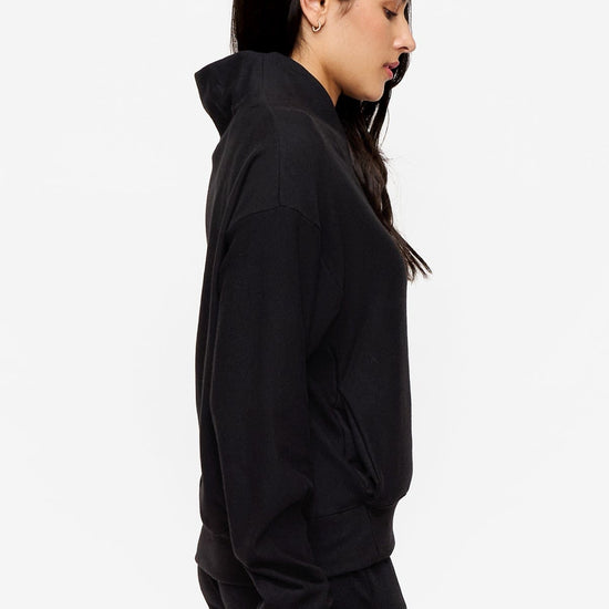 side of a woman wearing a 1/4 zip sweatshirt in black