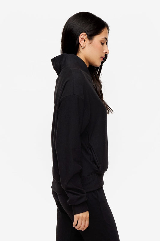 side of a woman wearing a 1/4 zip sweatshirt in black