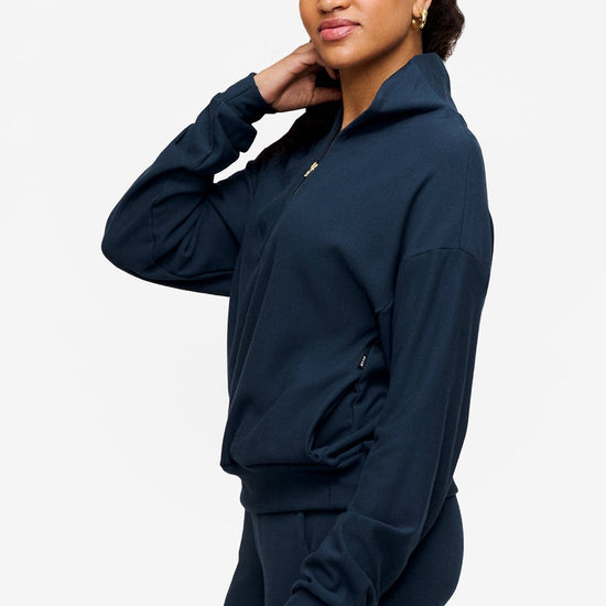 side of a woman wearing a 1/4 zip sweatshirt in deep blue