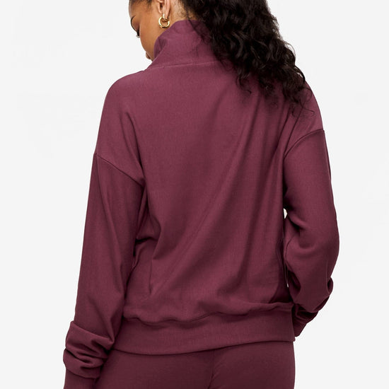 back of a woman wearing a 1/4 zip sweatshirt in deep pink