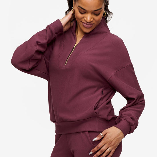 side o a woman wearing a 1/4 zip sweatshirt in deep pink