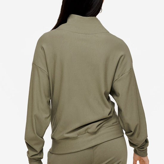 back of a woman wearing a 1/4 zip sweatshirt in green