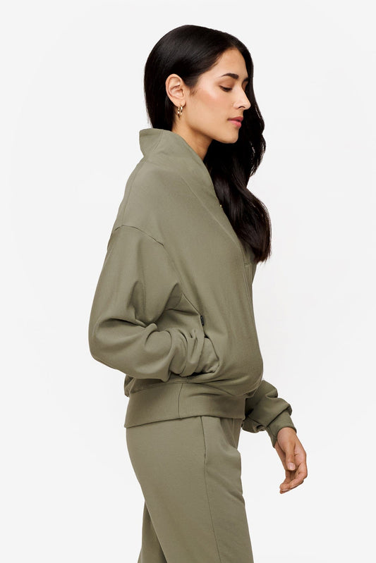 side of a woman wearing a 1/4 zip sweatshirt in green