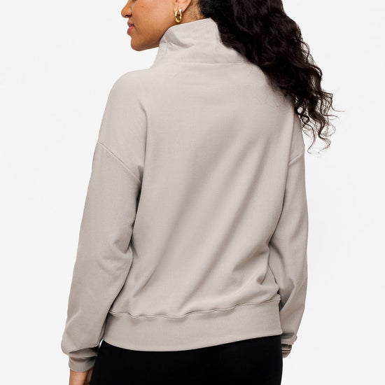 back of a woman wearing a 1/4 zip sweatshirt in grey