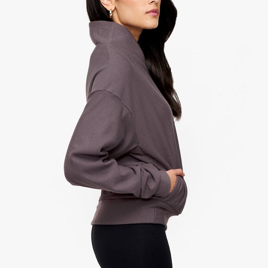 side of a woman wearing a 1/4 zip sweatshirt in deep purple