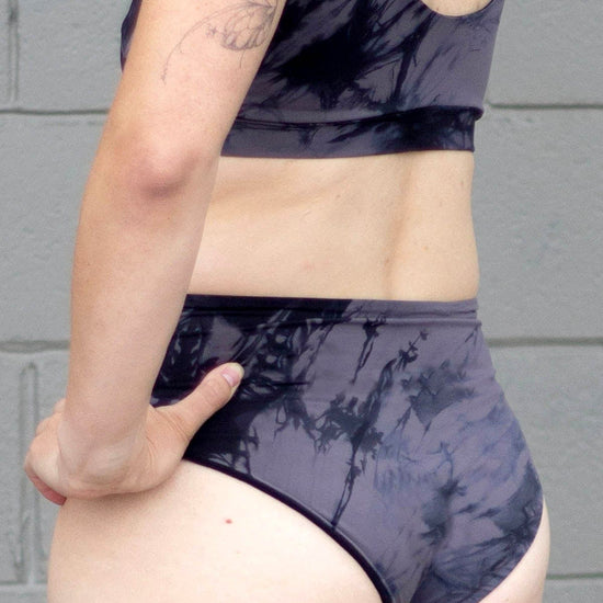 Back of a woman wearing grey tie-dye swim bottoms 