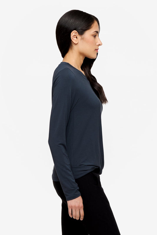 side of a woman wearing a long sleeve shirt with a twist at the front in dark blue