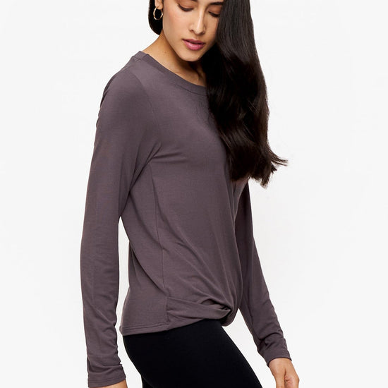 side of a woman wearing a long sleeve shirt with a twist at the front in deep purple