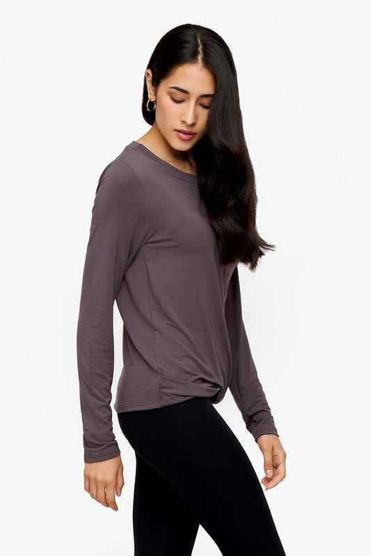 side of a woman wearing a long sleeve shirt with a twist at the front in deep purple