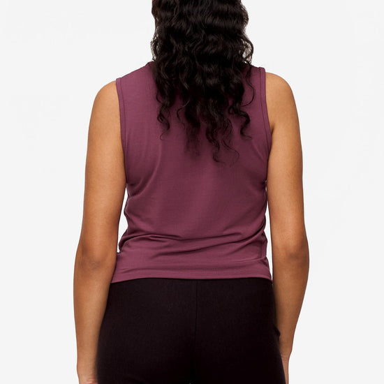 back of a woman wearing a sleeveless shirt with a twist at the front in deep pink