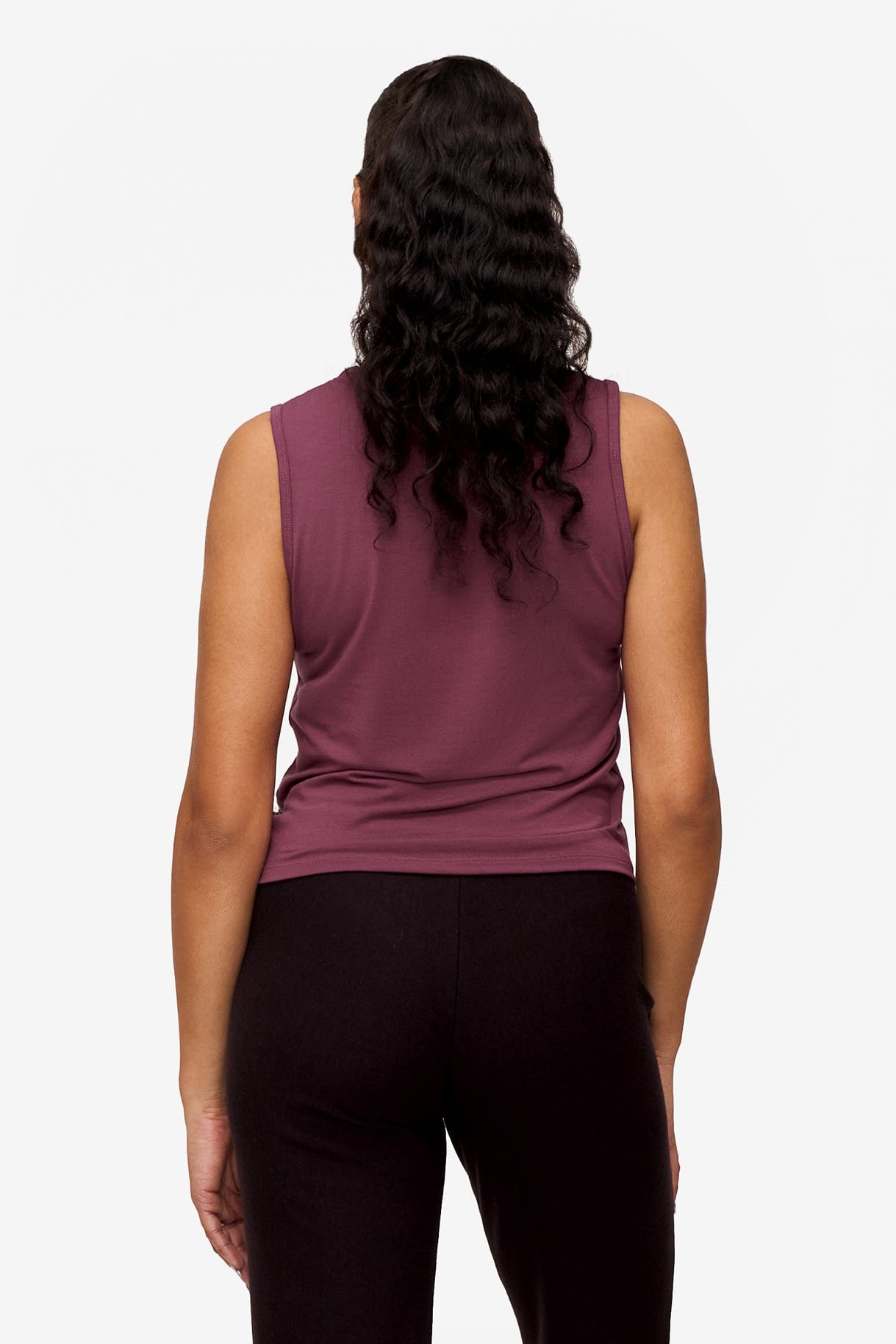 back of a woman wearing a sleeveless shirt with a twist at the front in deep pink