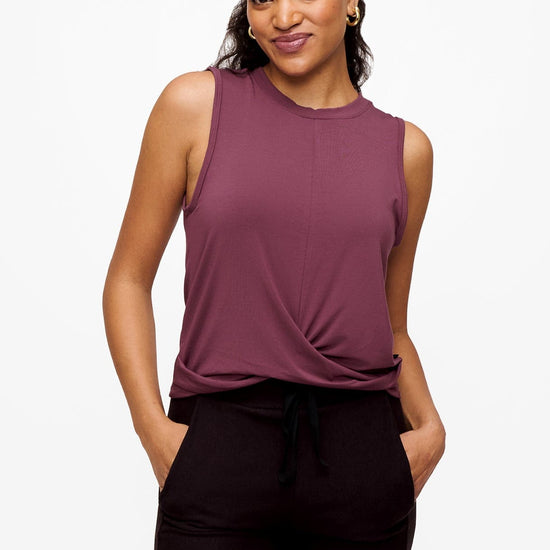 woman wearing a sleeveless shirt with a twist at the front in deep pink with here hands in the pockets